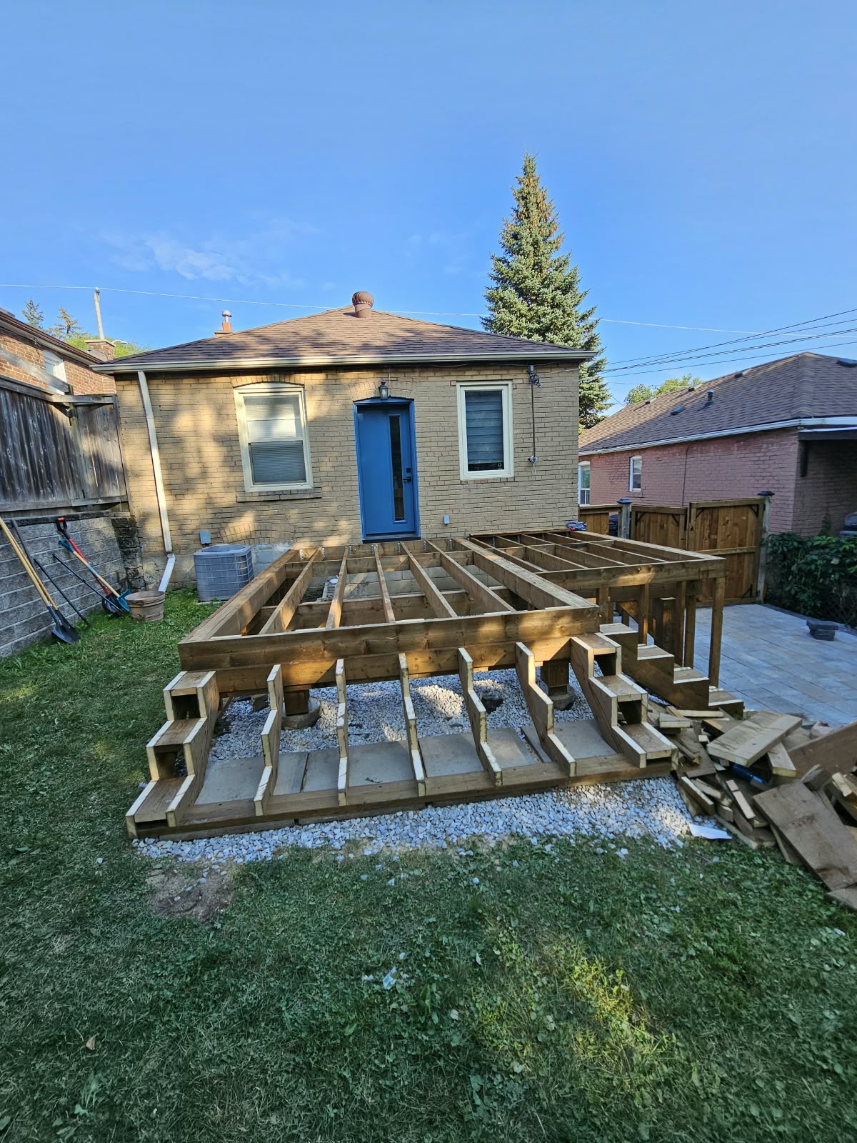 Pressure-treated deck frame and stair stringers behind a brick home