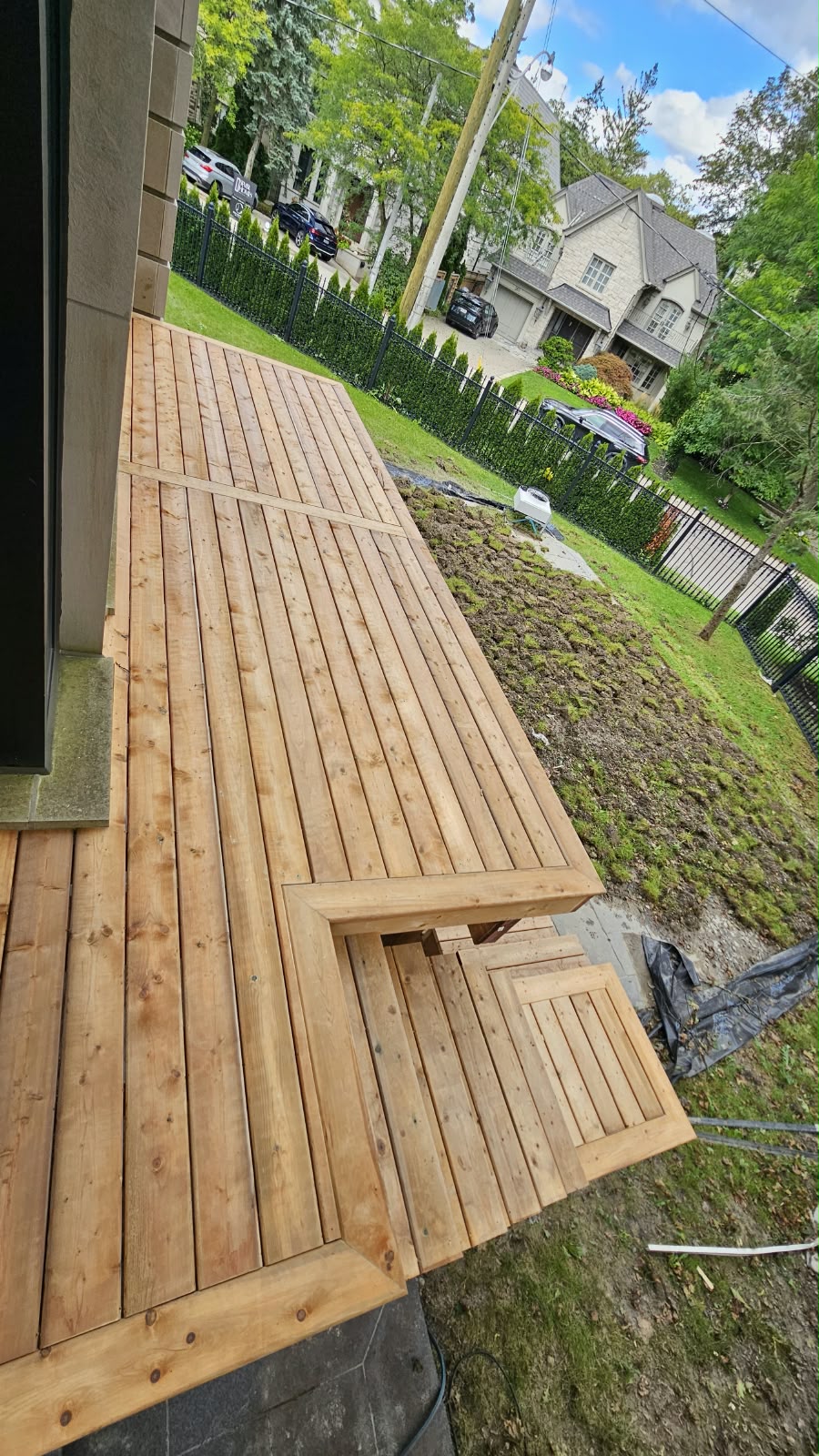 Large cedar deck with multi-level steps overlooking a front lawn