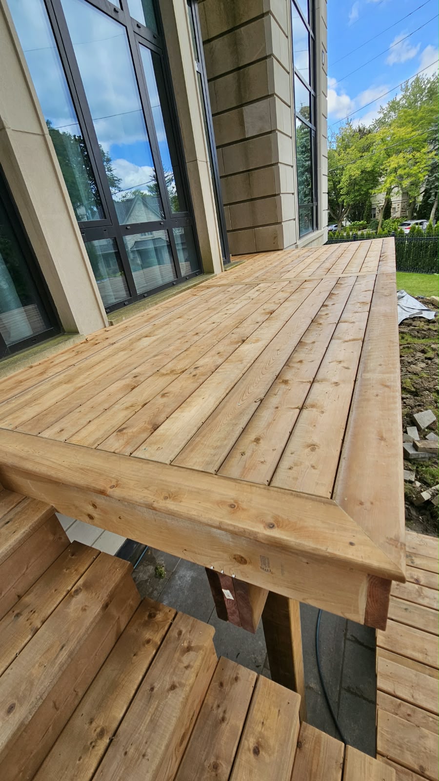 Cedar deck boards with picture-frame border along a stone home