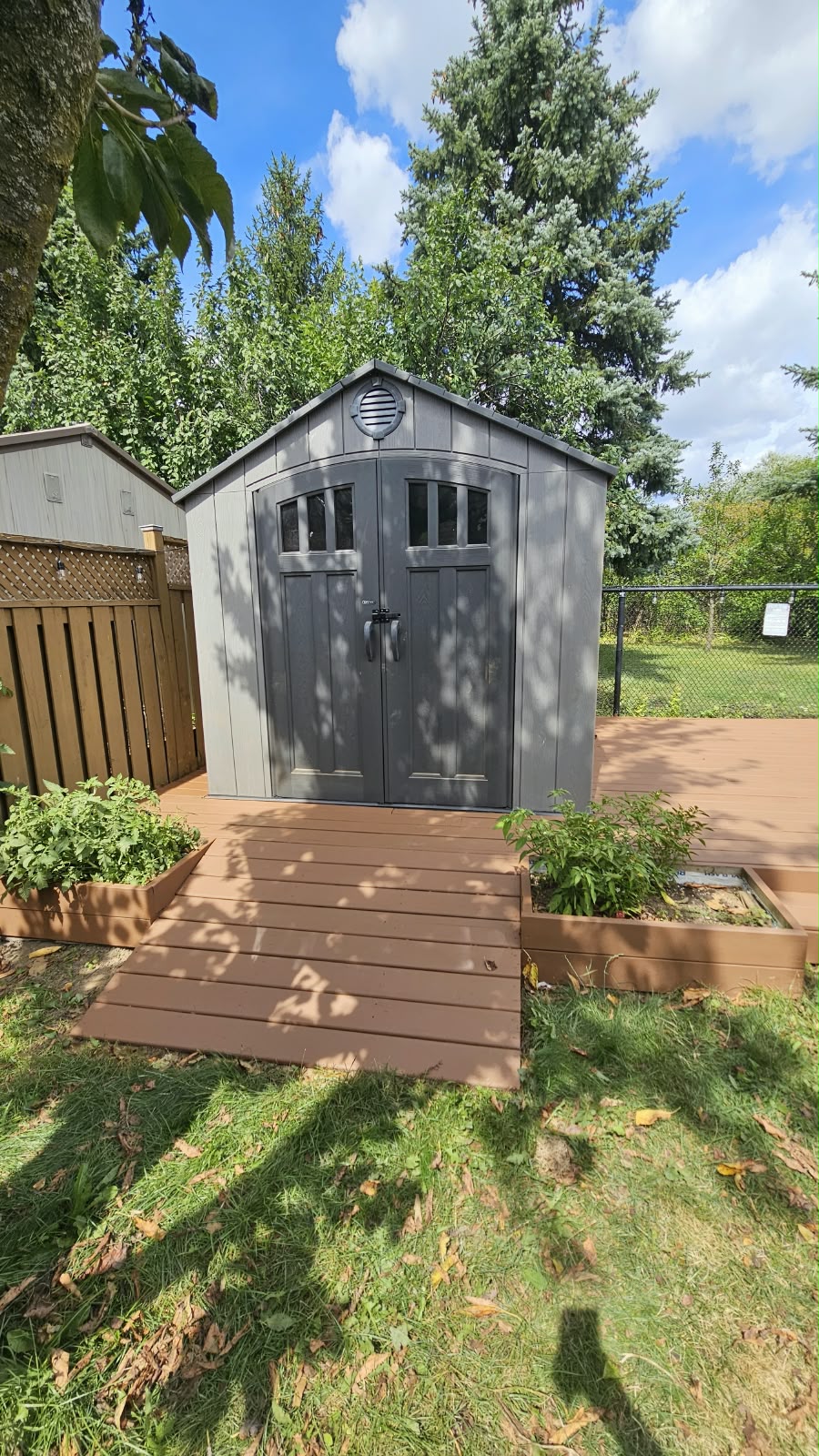 Composite deck platform built around a storage shed with planter boxes